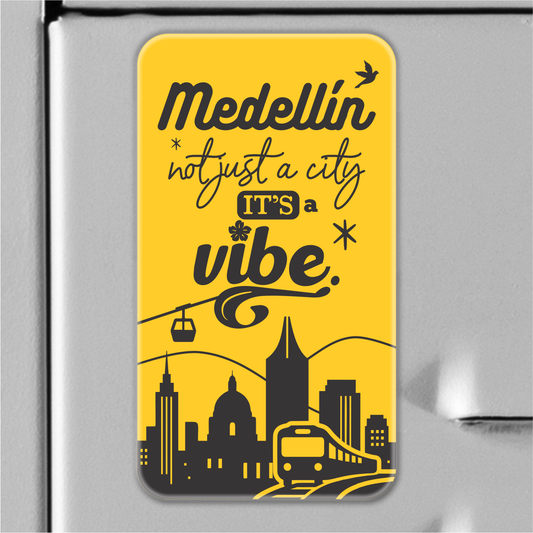 Yellow magnet souvenir with Medellín skyline, cable car and train, phrase "Medellín not just a city, it’s a vibe".